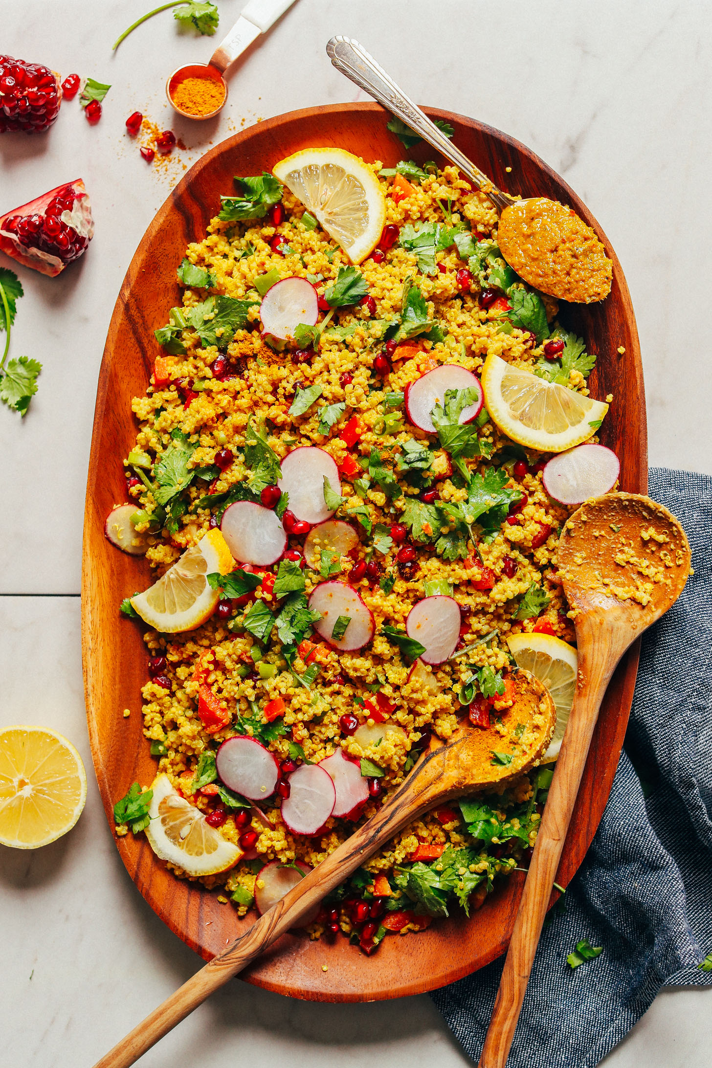 Large wood platter with Curried Quinoa Salad served with fresh vegetables and lemon slices