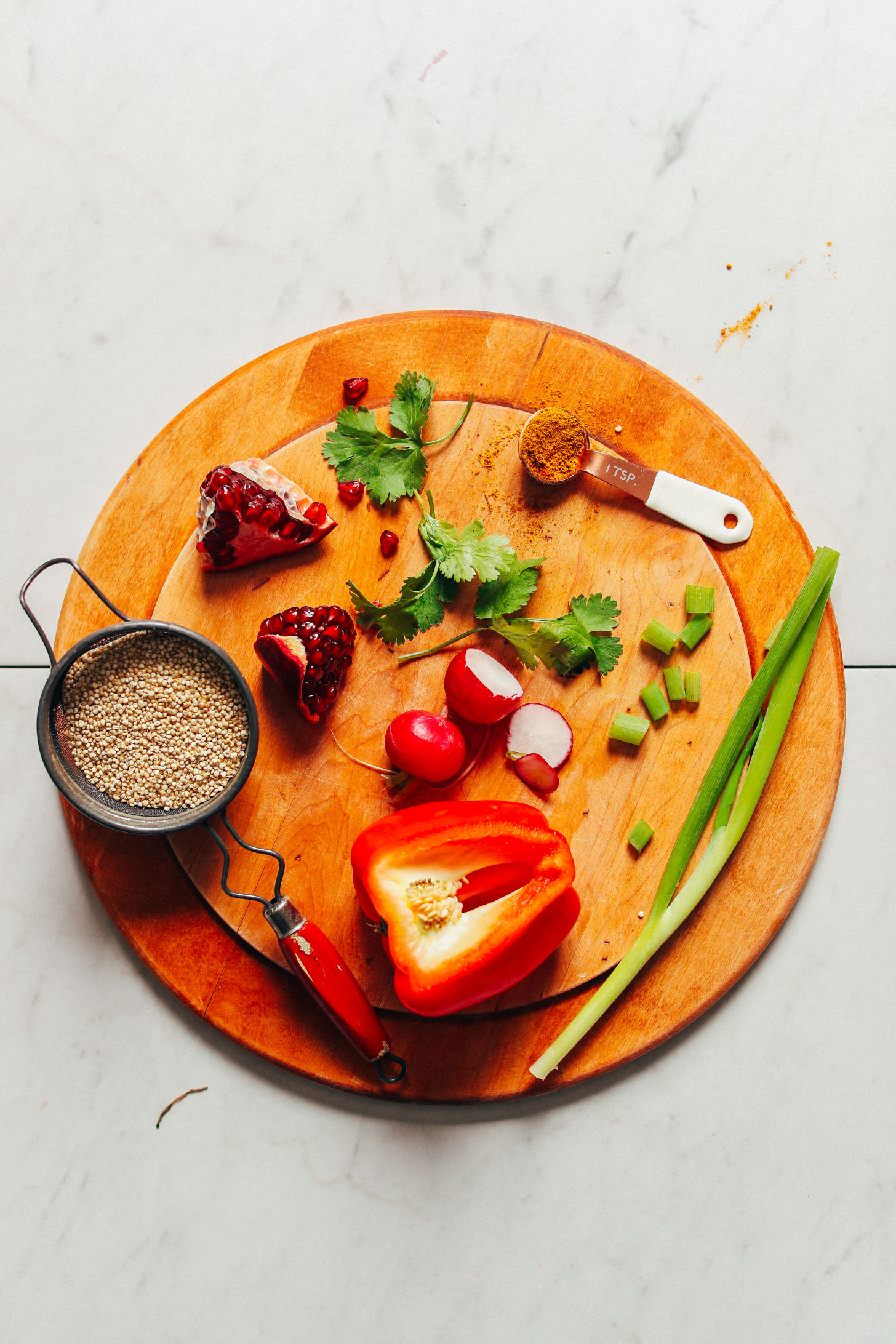 Pomegranate seeds, quinoa, cilantro, radishes, green onion, red bell pepper, and curry powder are featured in this photo for making Curried Quinoa Salad