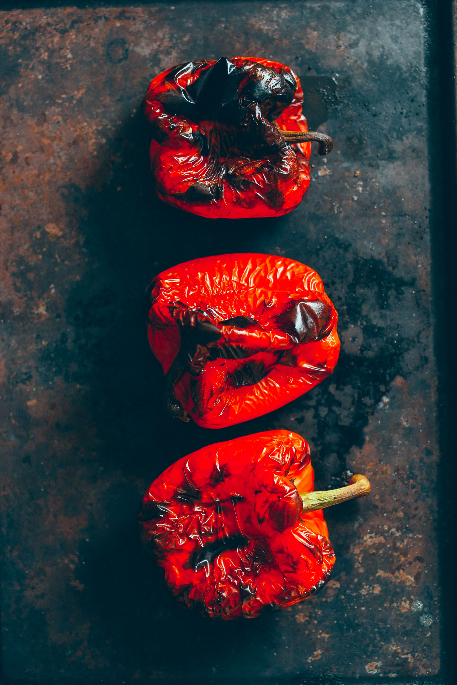 Charred red bell peppers on a baking sheet ready for making Muhamarra Dip