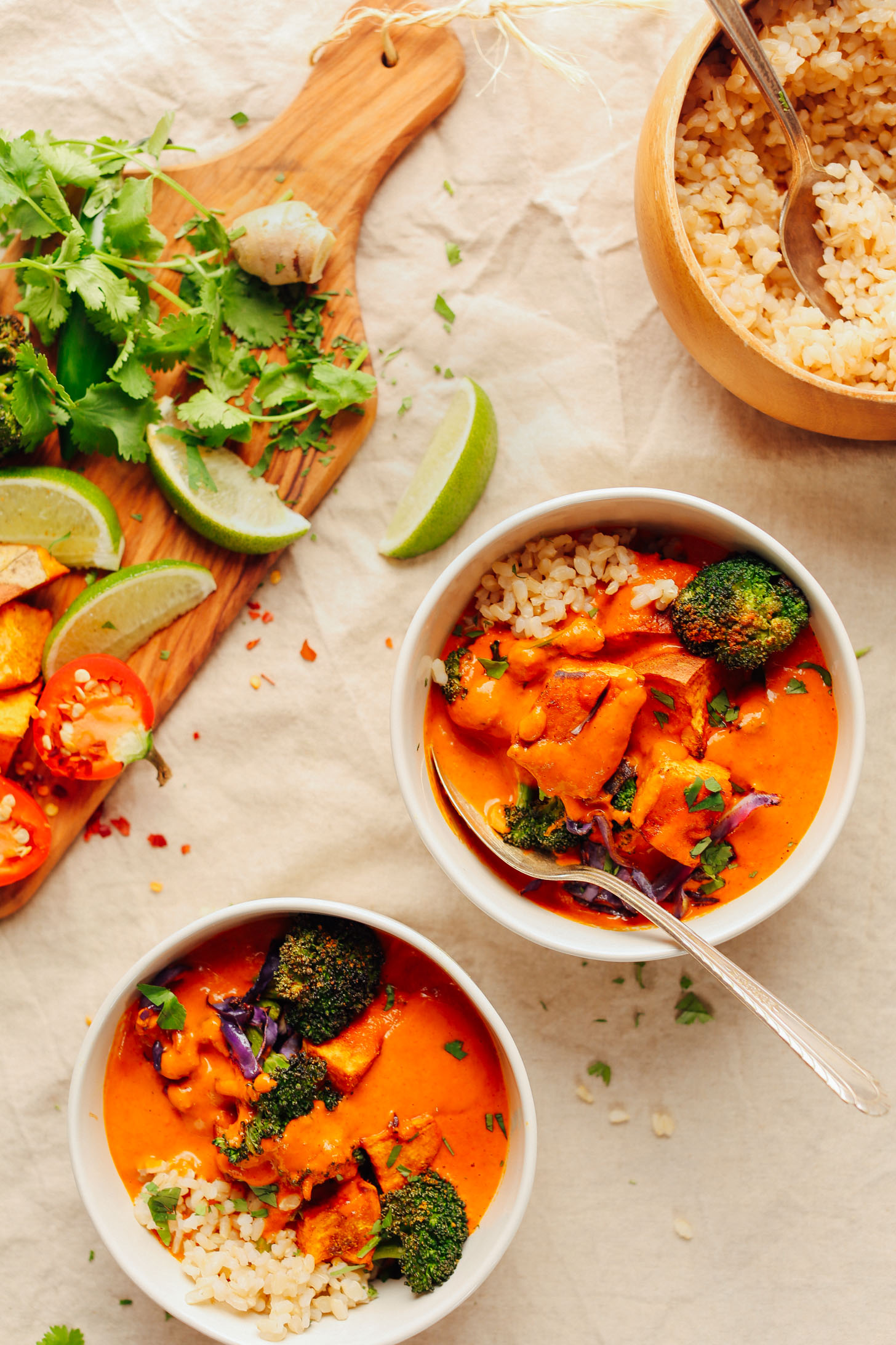 Two bowls of Rich Red Curry served with rice and fresh garnishes of lime and cilantro