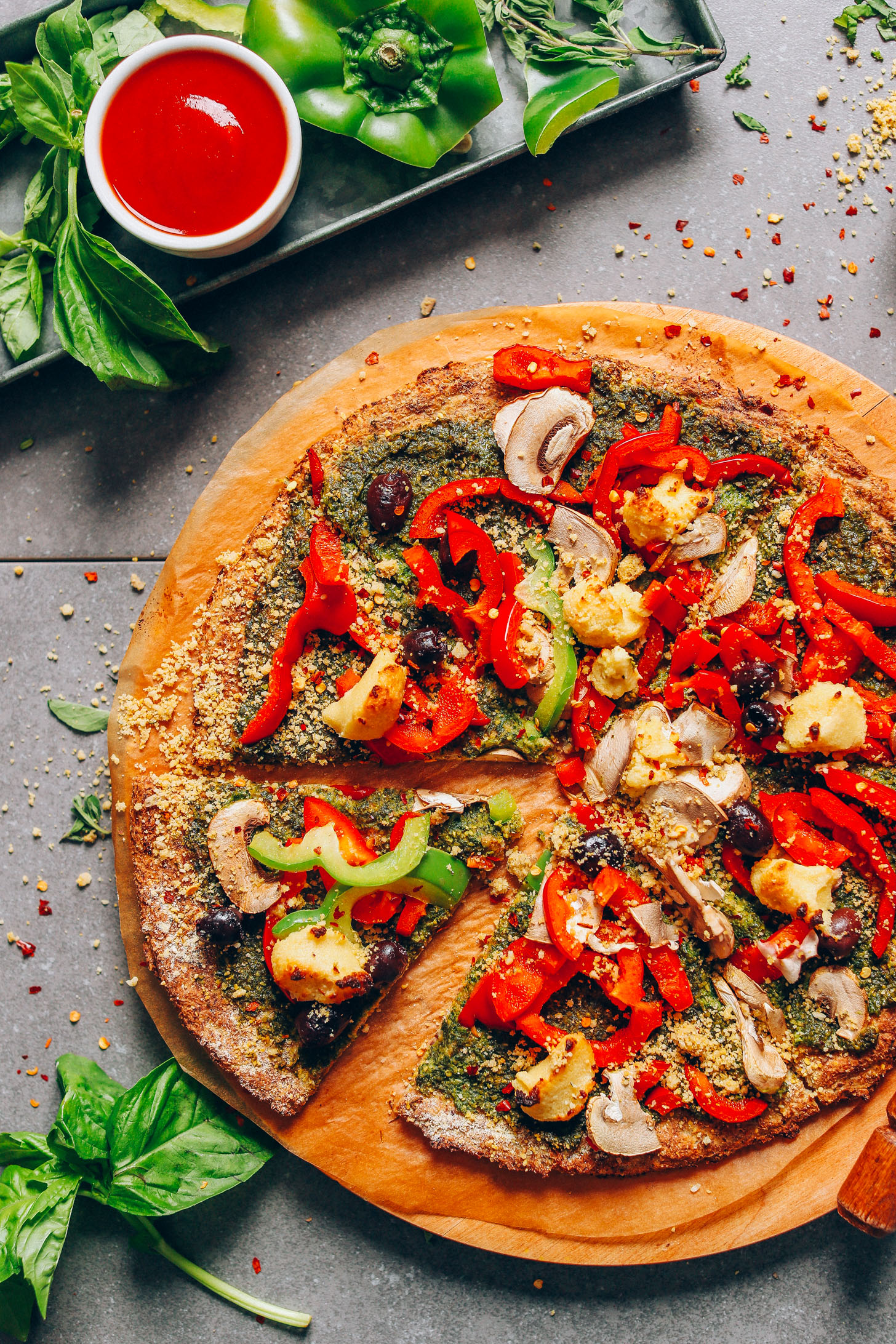 Freshly sliced, veggie-loaded pizza made with our vegan Gluten-Free Cauliflower Pizza Crust recipe