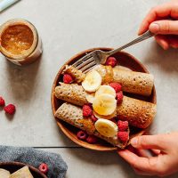 Using a fork to grab a bite of Gluten-Free Buckwheat Crepes topped with fresh fruit
