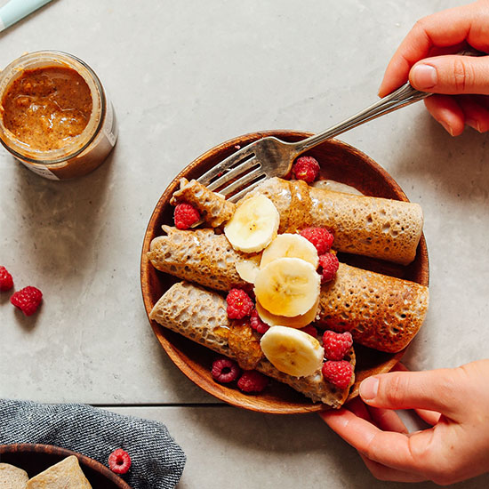 Using a fork to grab a bite of Gluten-Free Buckwheat Crepes topped with fresh fruit