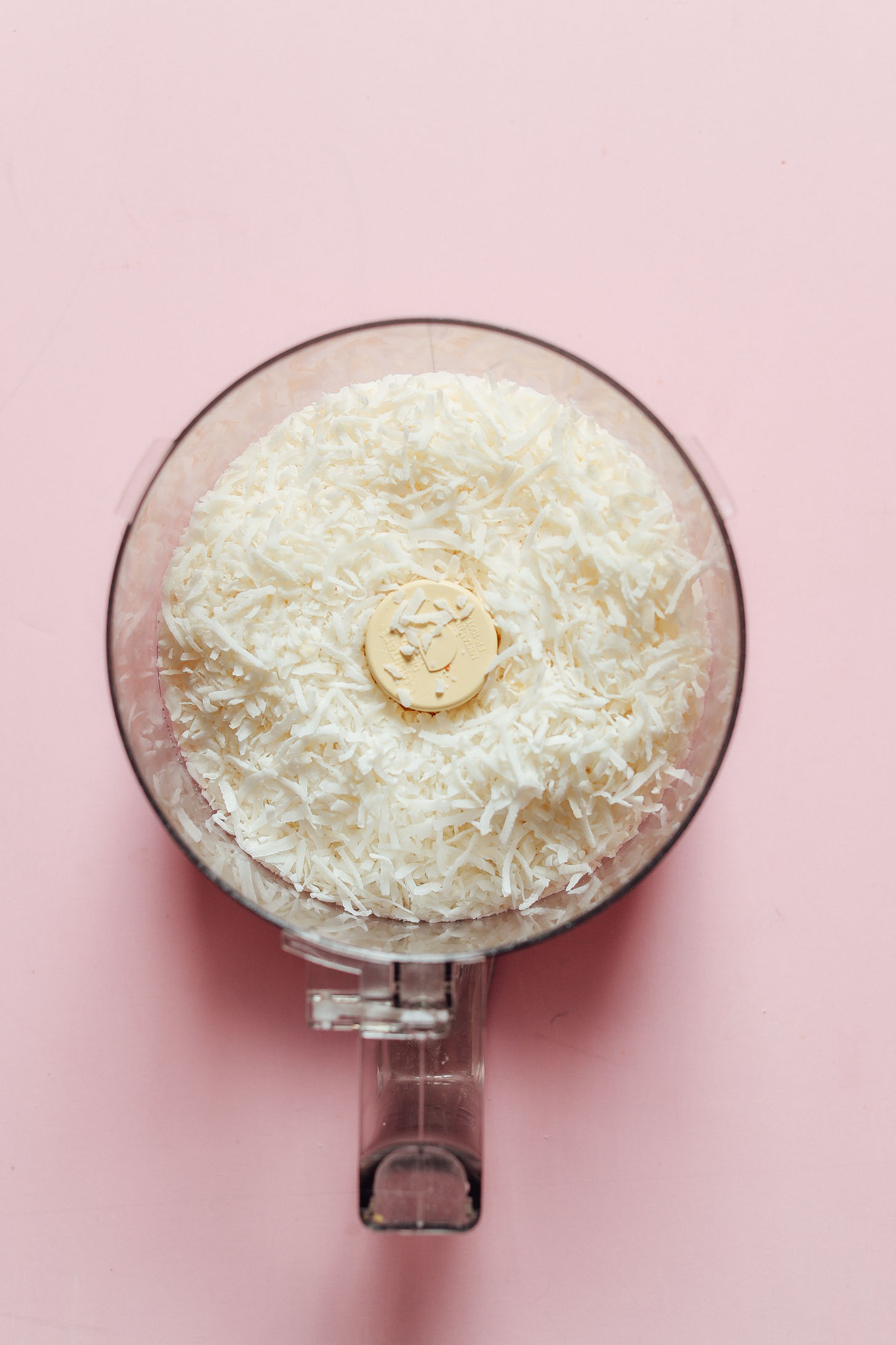 Food processor filled with shredded coconut for making Coconut Snowball Cookies