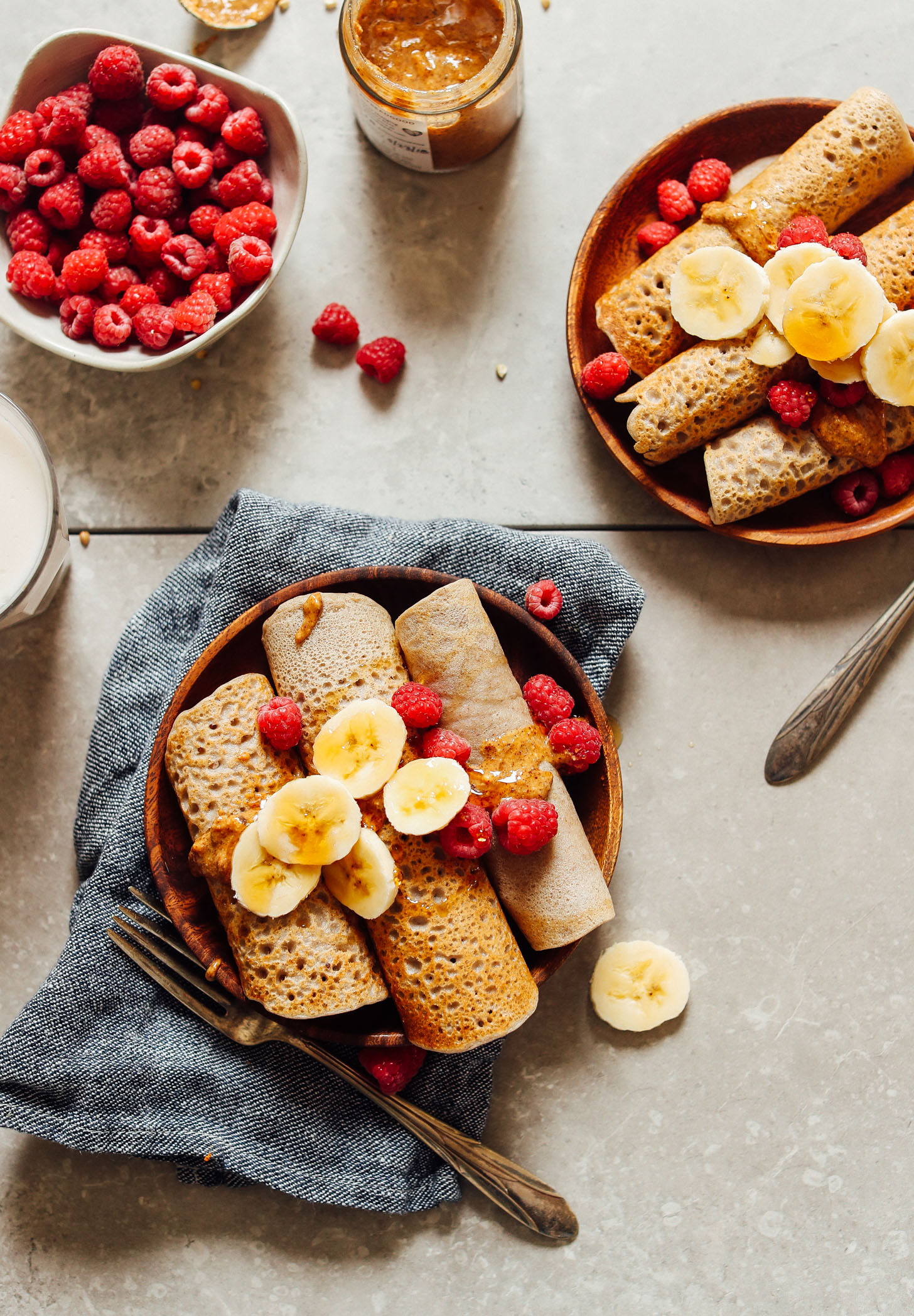 Overhead shot of vegan gluten free buckwheat crepes with bananas and berries and nut butter