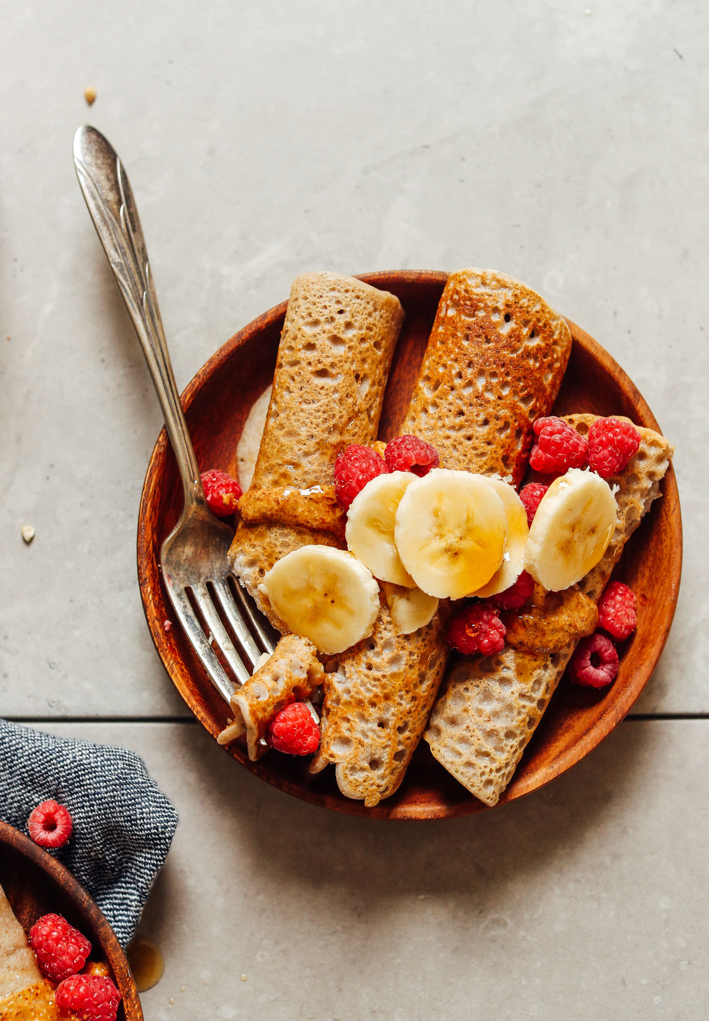 Plate with a fork and three Vegan Buckwheat Crepes topped with fresh fruit