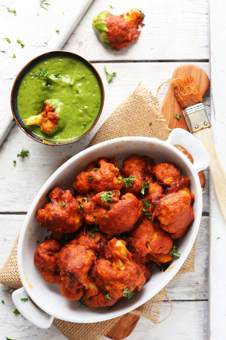 Red Curry Cauliflower in a dish and dipped in green chutney for a Plant-Based Super Bowl Snack