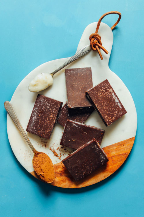 Sugar-Free Coconut Carob Bars arranged on a white marble cutting board with spoonfuls of coconut butter and toasted carob powder