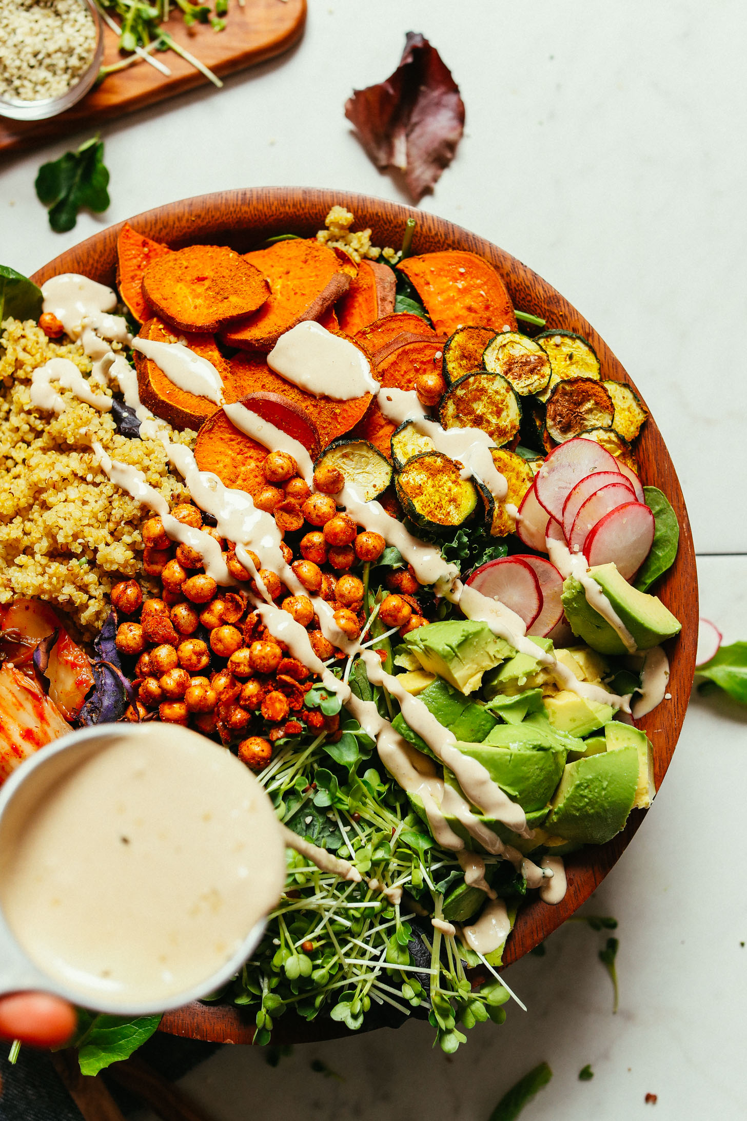 Drizzling Savory Tahini Dressing over our healthy, colorful Abundance Green Salad
