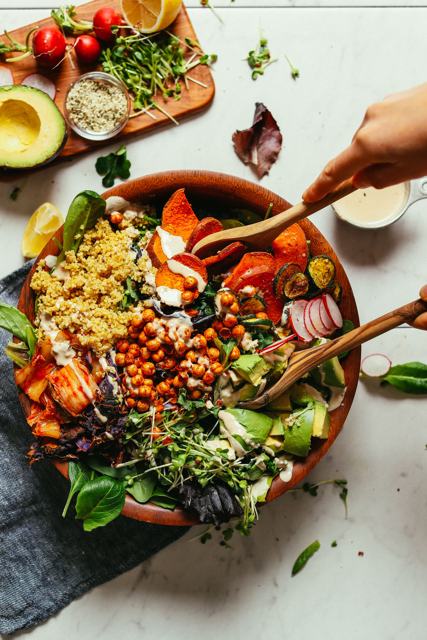 Using salad tongs to grab a hearty serving of our healthy vegan Abundance Green Salad with Savory Tahini Dressing