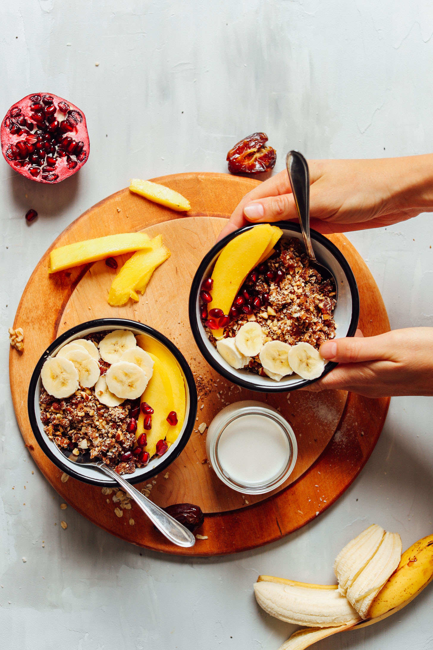 Two bowls of our gluten-free Rawnola served with dairy-free milk and fresh fruit
