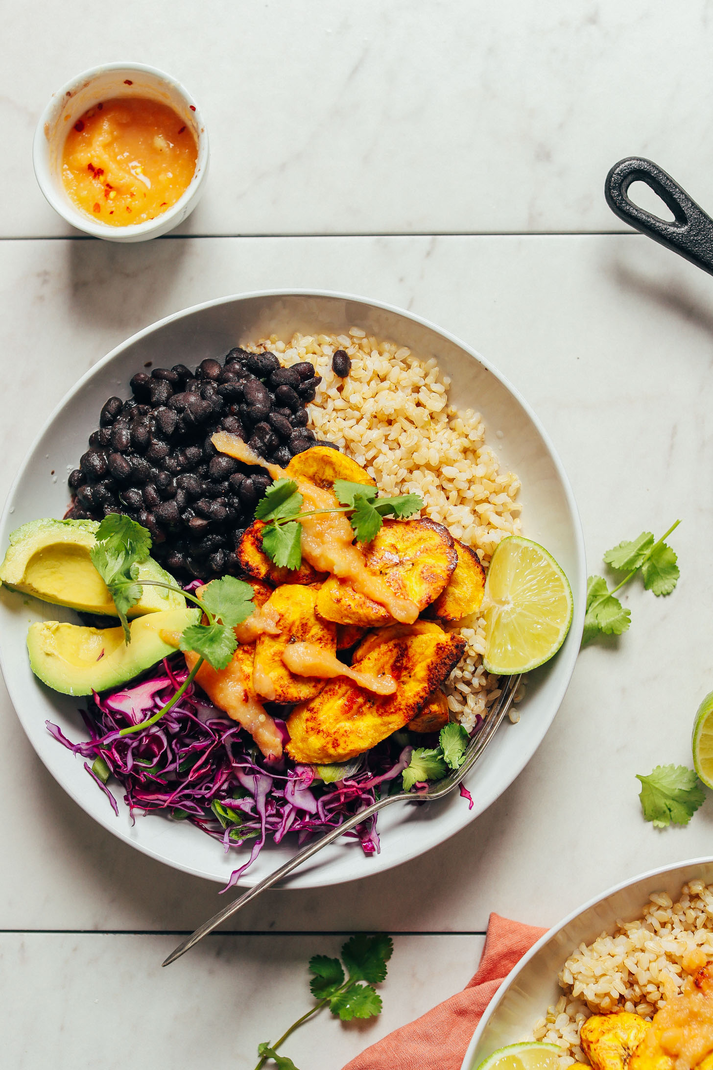 Delicious, satisfying serving of Black Bean Plantain Bowls with a small side of homemade hot sauce