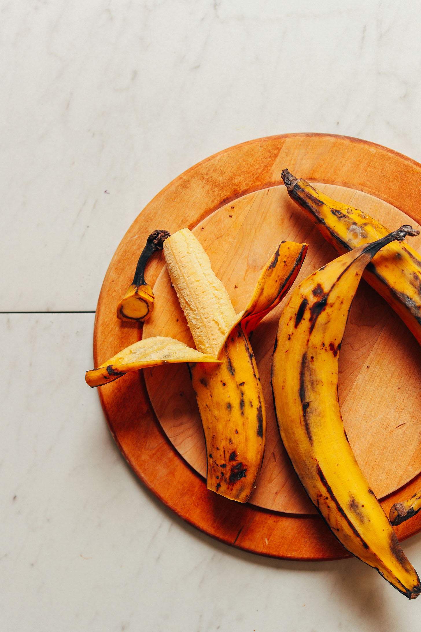 Wood cutting board displaying ripe plantains ready to be turned into delicious Black Bean Plantain Bowls