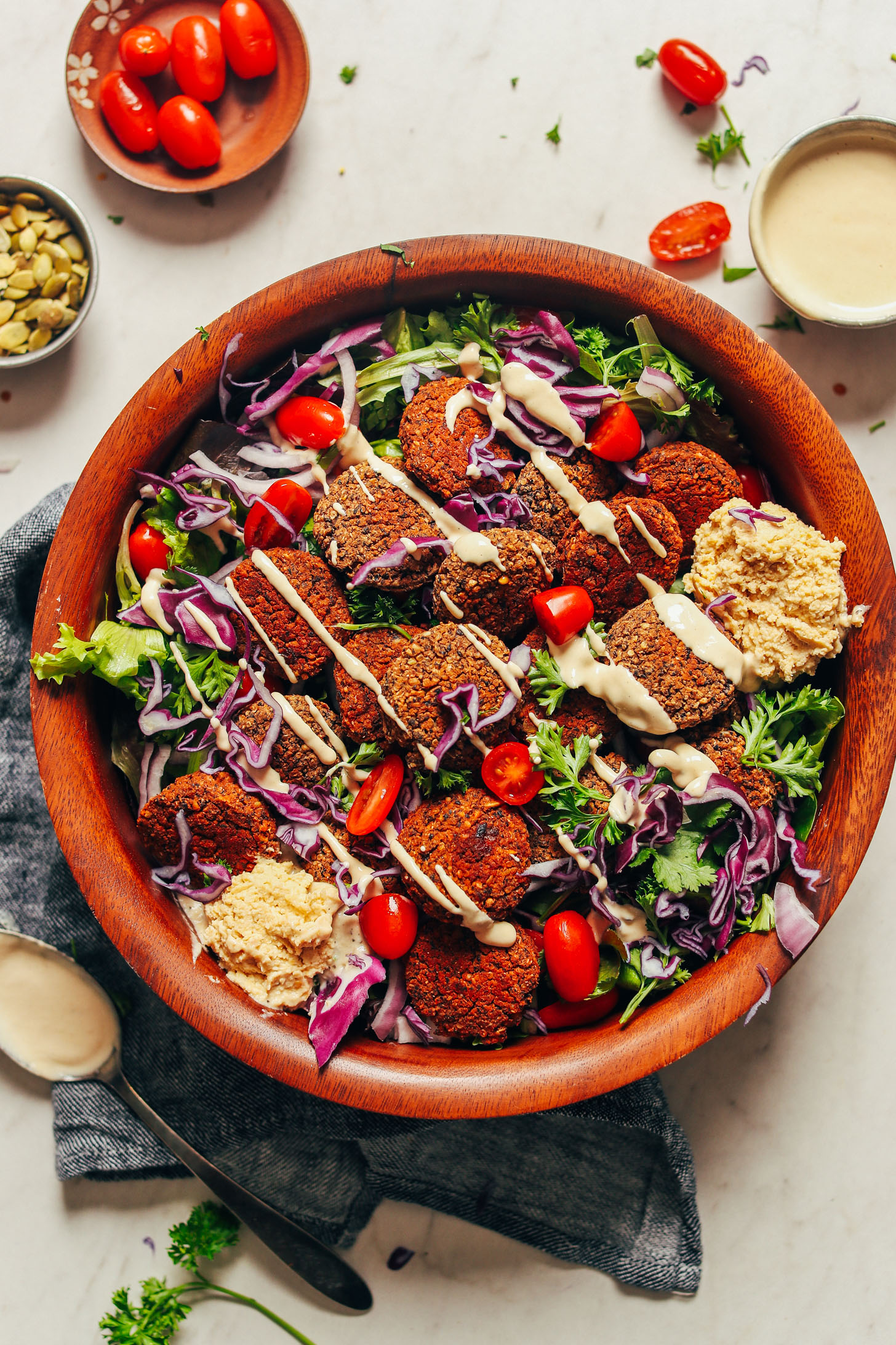 Large serving bowl featuring Black Bean Quinoa Falafel on top of fresh greens and other vegetables