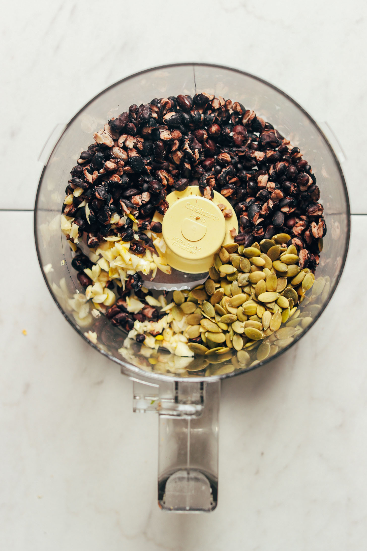 Black beans, pumpkin seeds, and garlic in a food processor ready to be turned into delicious gluten-free Black Bean Quinoa Falafel