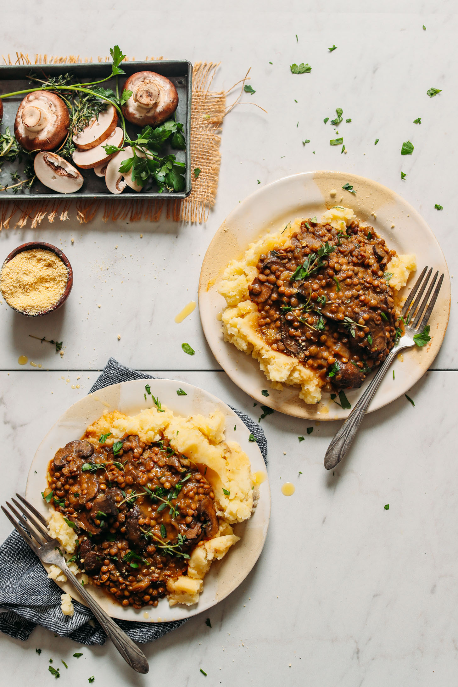 Plates of Lentil Mushroom Stew topped with fresh thyme served over mashed potatoes