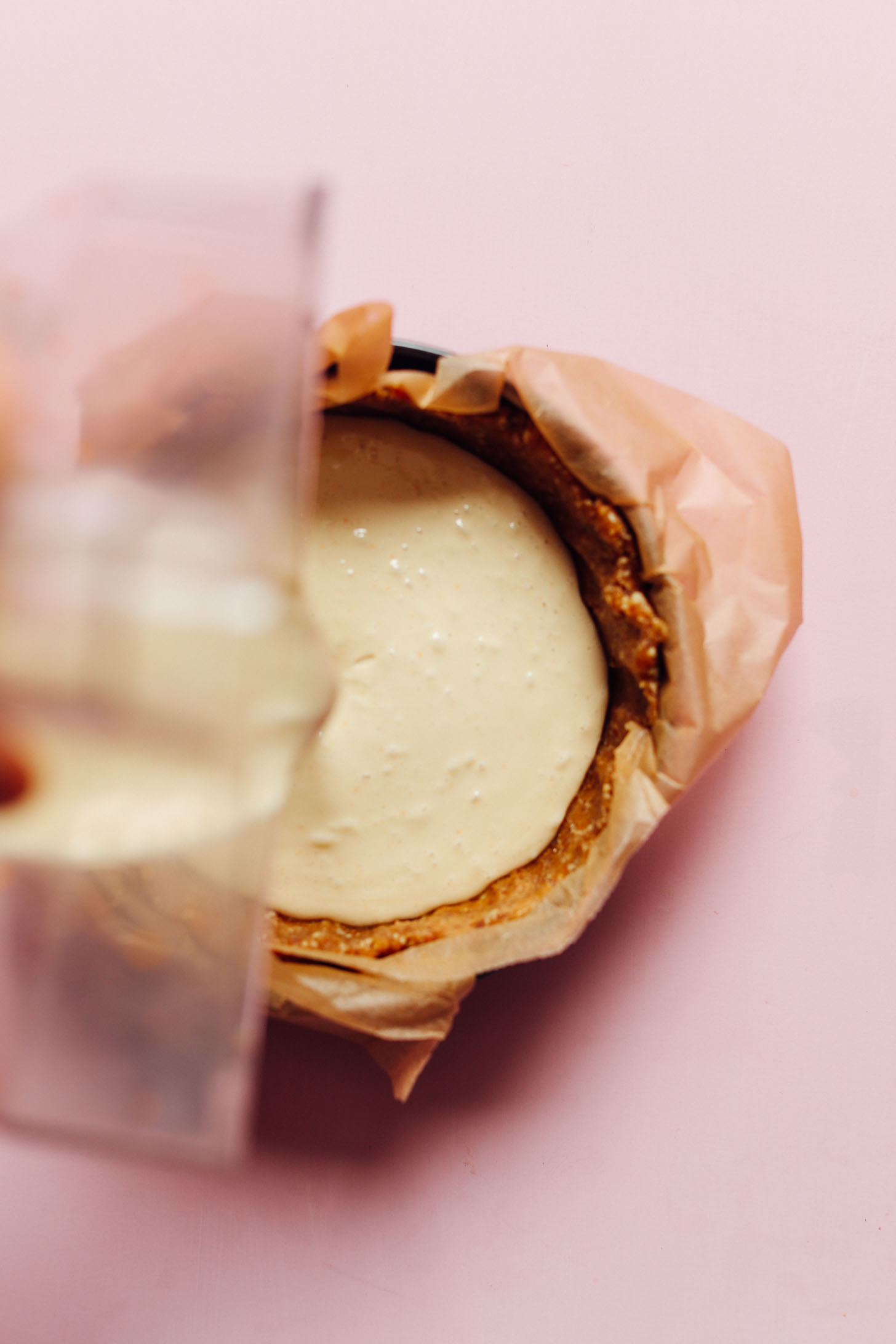 Pouring Coconut Yogurt Cheesecake filling into gluten-free crust