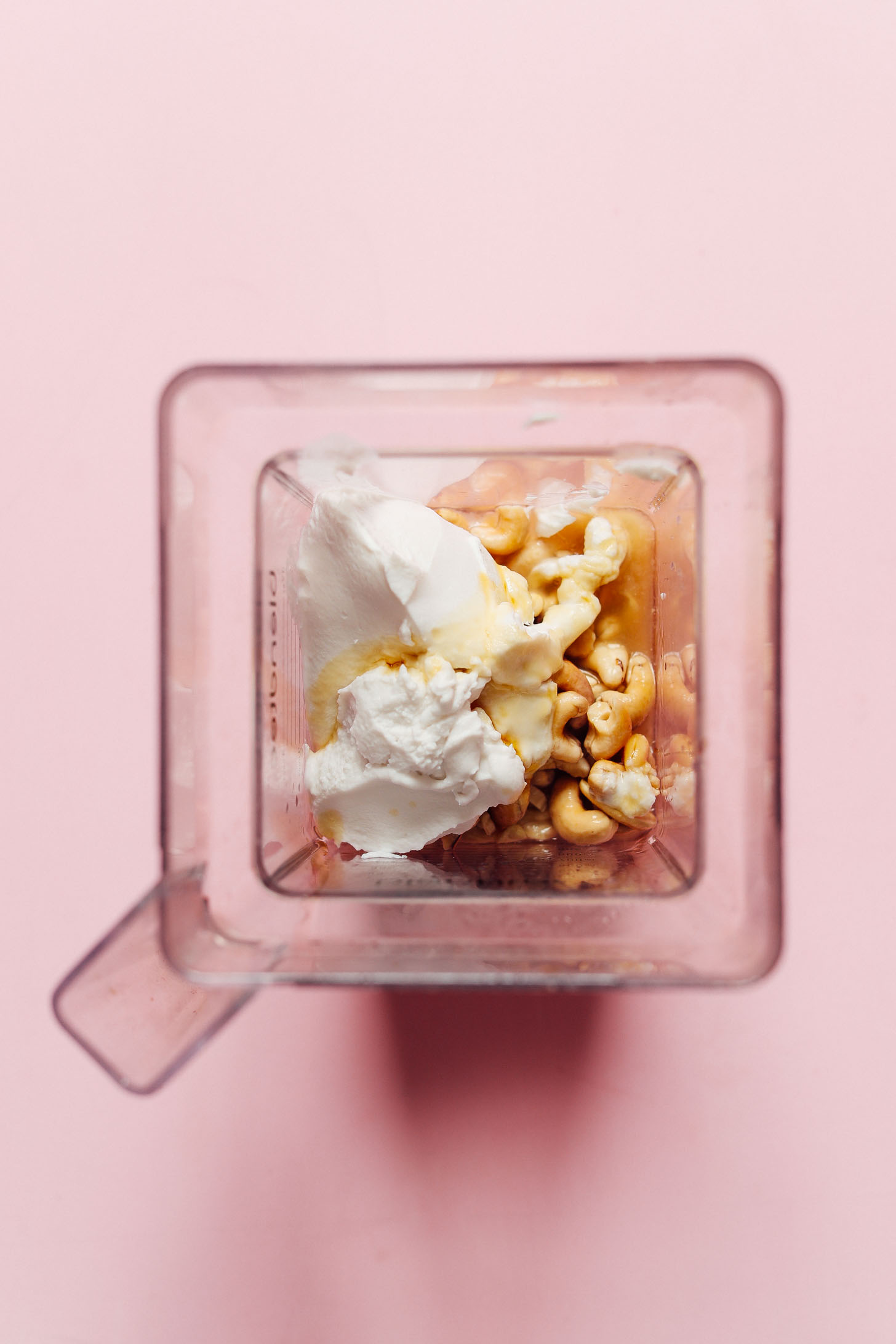 A blender full of cashews, vanilla, citrus zest, lemon juice, coconut oil, maple syrup, and salt for making vegan Coconut Yogurt Cheesecake