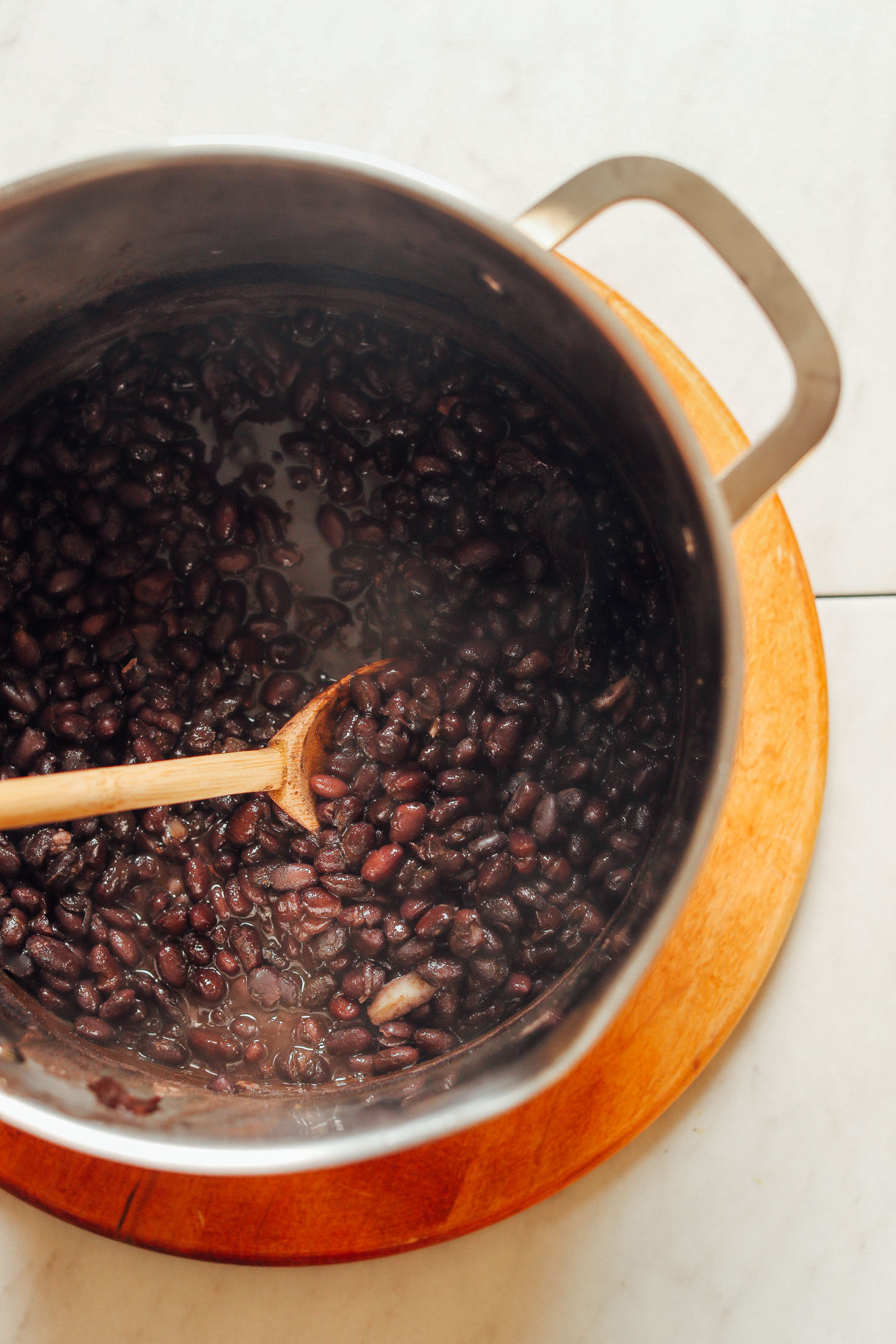 Stirring a large pot of tender, flavorful homemade black beans created using our Easy 1-Pot Black Beans recipe