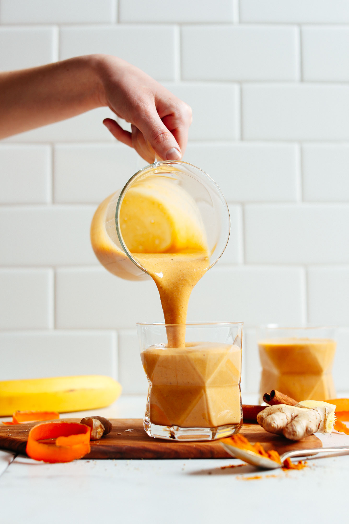 Pouring our vibrantly-colored Vegan Golden Milk Smoothie into a serving glass