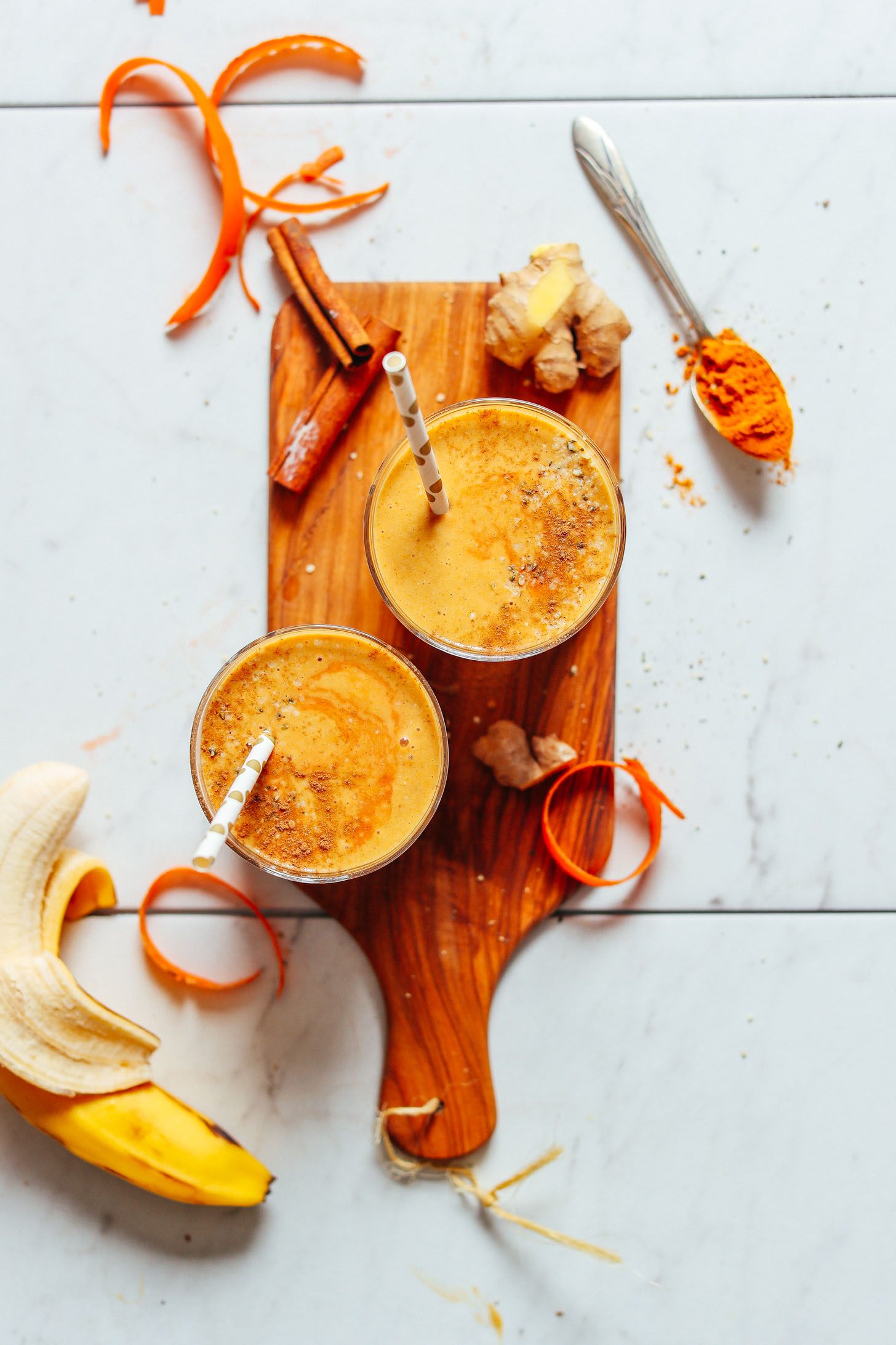 Top view shot of two serving glasses containing our Vegan Golden Milk Smoothie with an extra swirl of spices