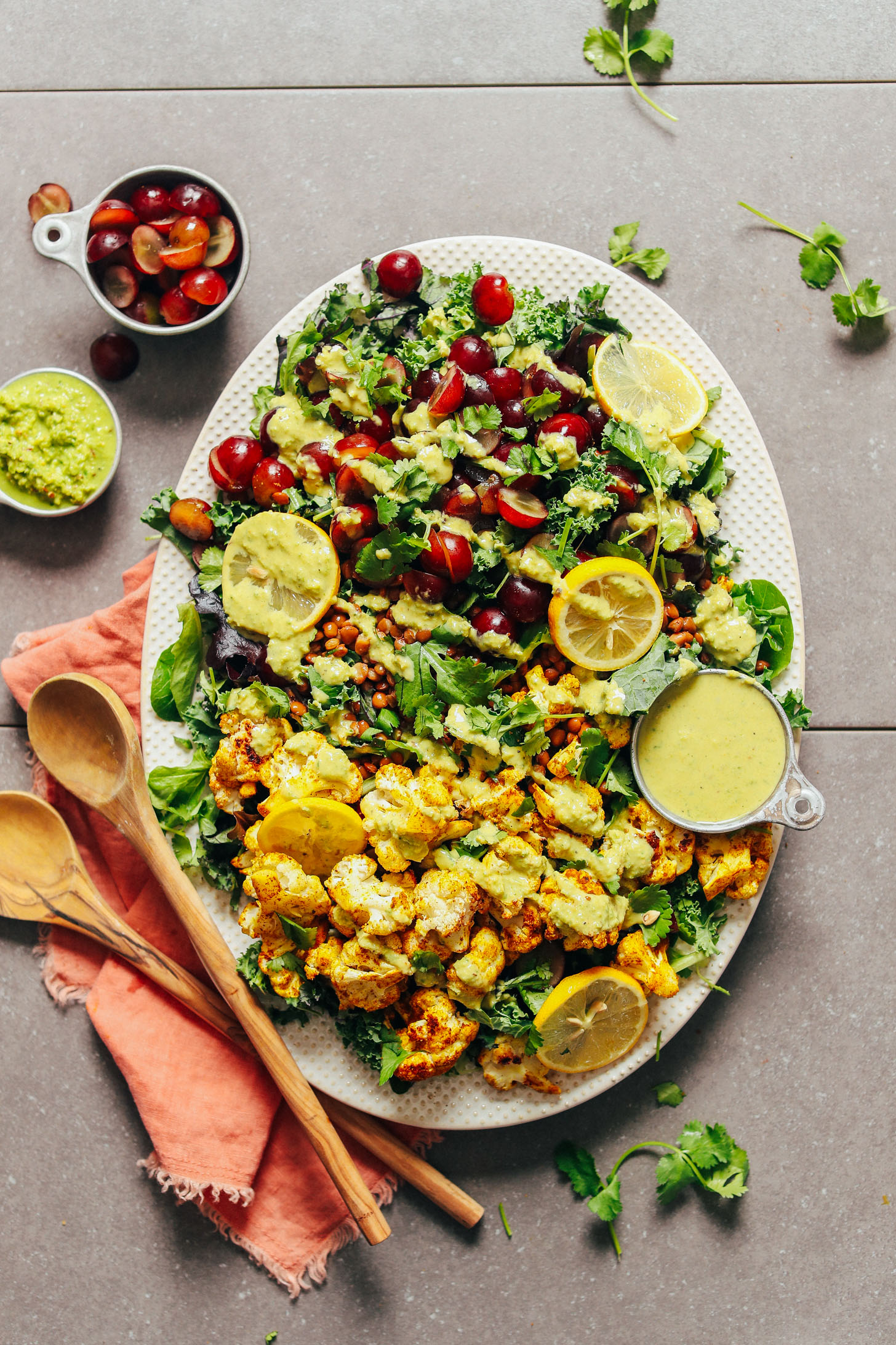 Serving platter displaying this hearty Kale Salad with Grapes, Lentils, and Curry Roasted Cauliflower