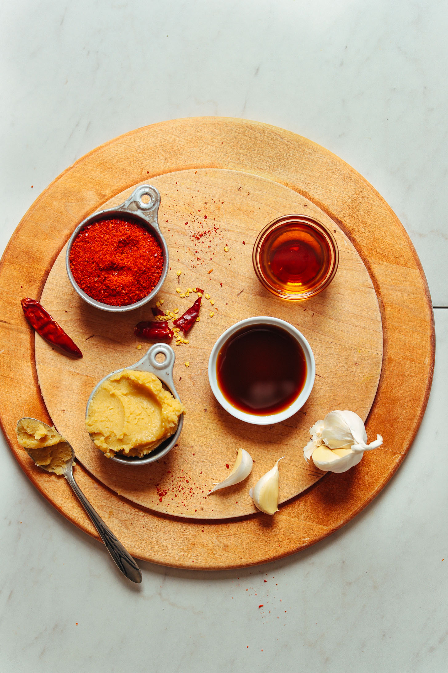 Wood cutting board with chili flakes, miso, coconut aminos, garlic, and maple syrup