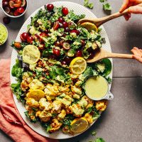Using wooden salad spoons to pick up a serving of Lentil Grape Cauliflower Salad
