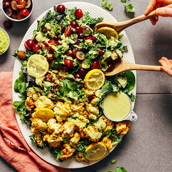 Using wooden salad spoons to pick up a serving of Lentil Grape Cauliflower Salad