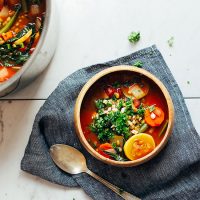 Blue linen with a spoon and bowl of Vegan Tomato Veggie Mung Bean Soup