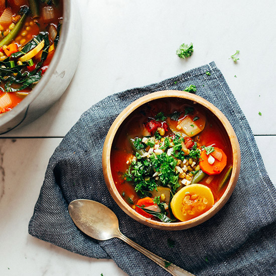 Blue linen with a spoon and bowl of Vegan Tomato Veggie Mung Bean Soup