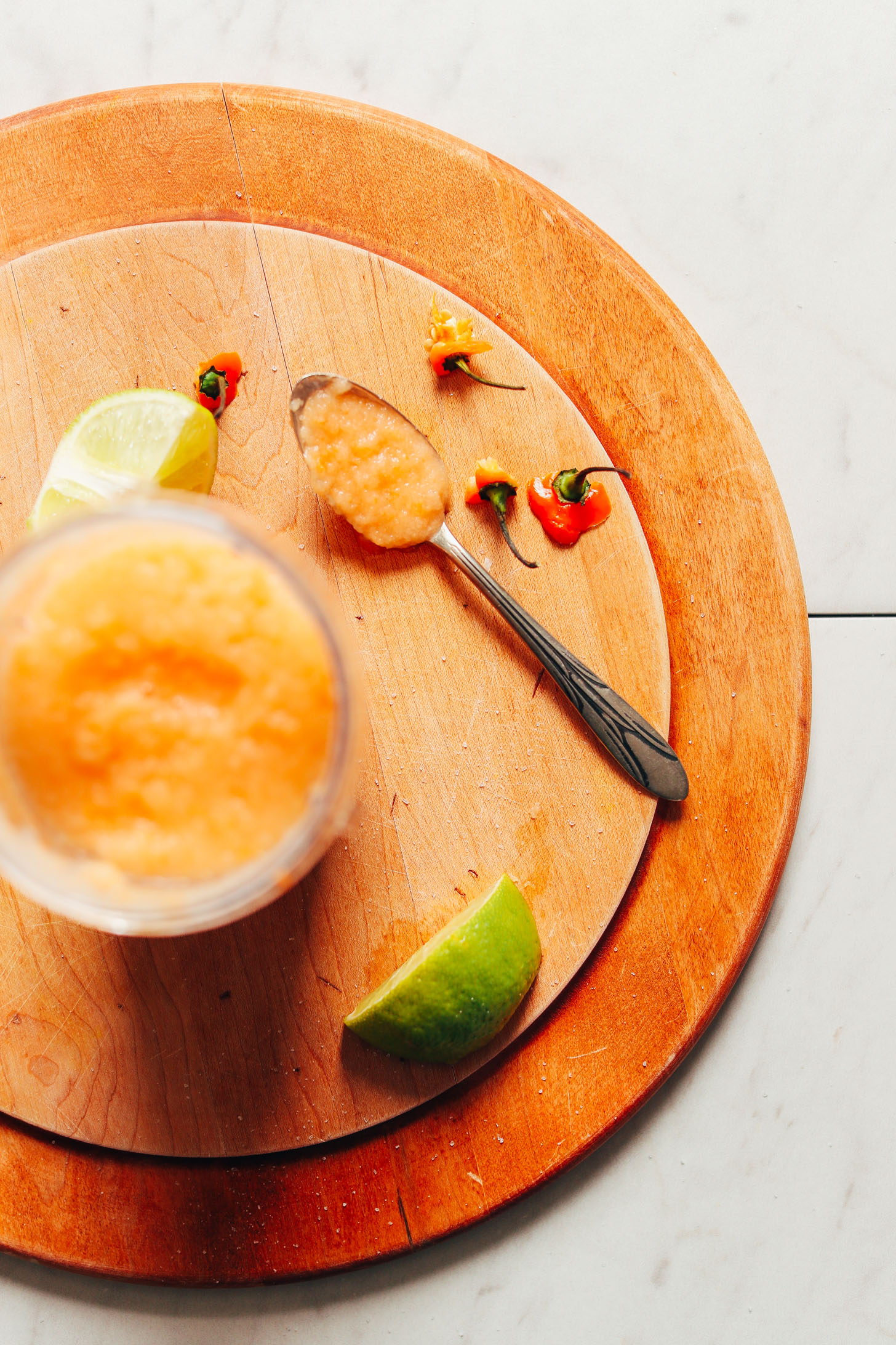 Habanero hot sauce on a wood cutting board with limes and habanero stems
