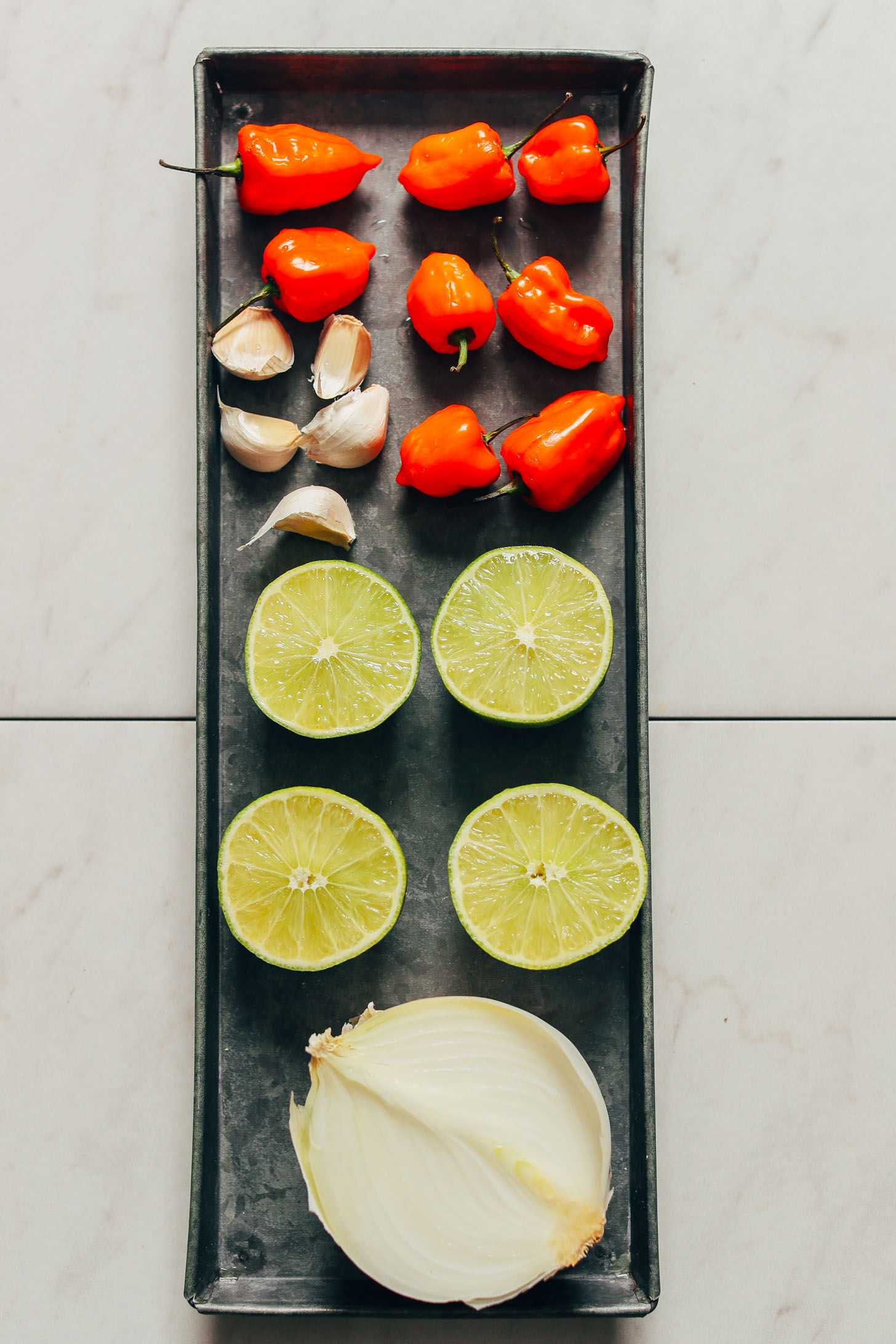 Platter of garlic, limes, onion, and habaneros for making homemade hot sauce