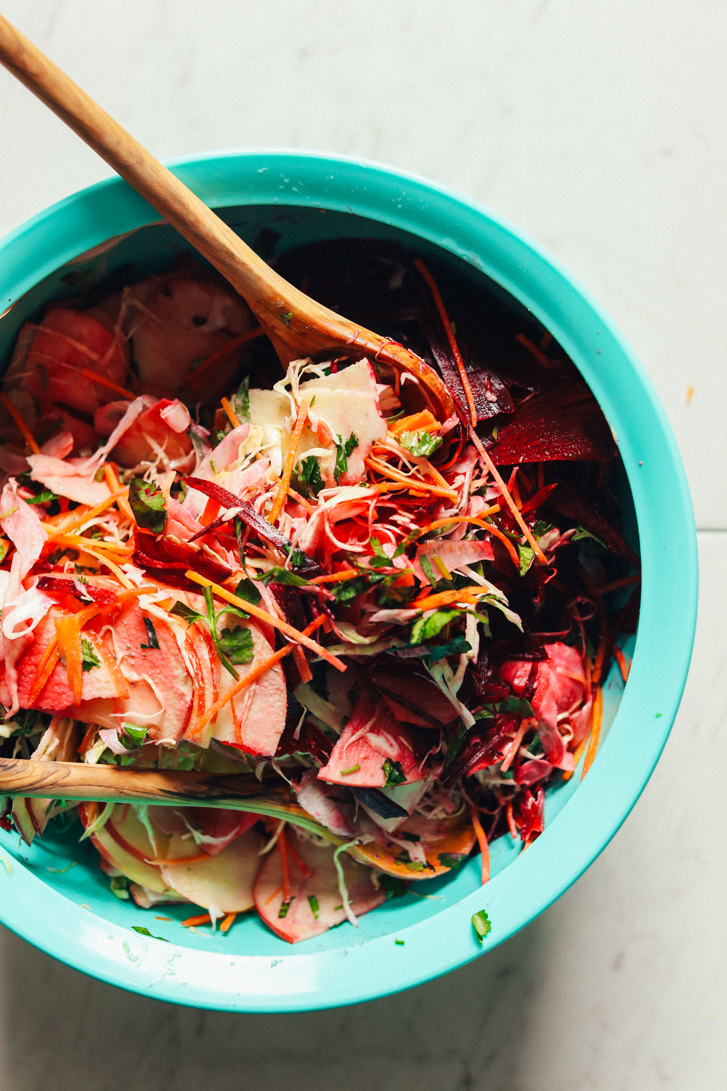 Bright blue serving bowl filled with fresh vegetables for Super Cleaning Slaw with Rosemary Tahini Dressing
