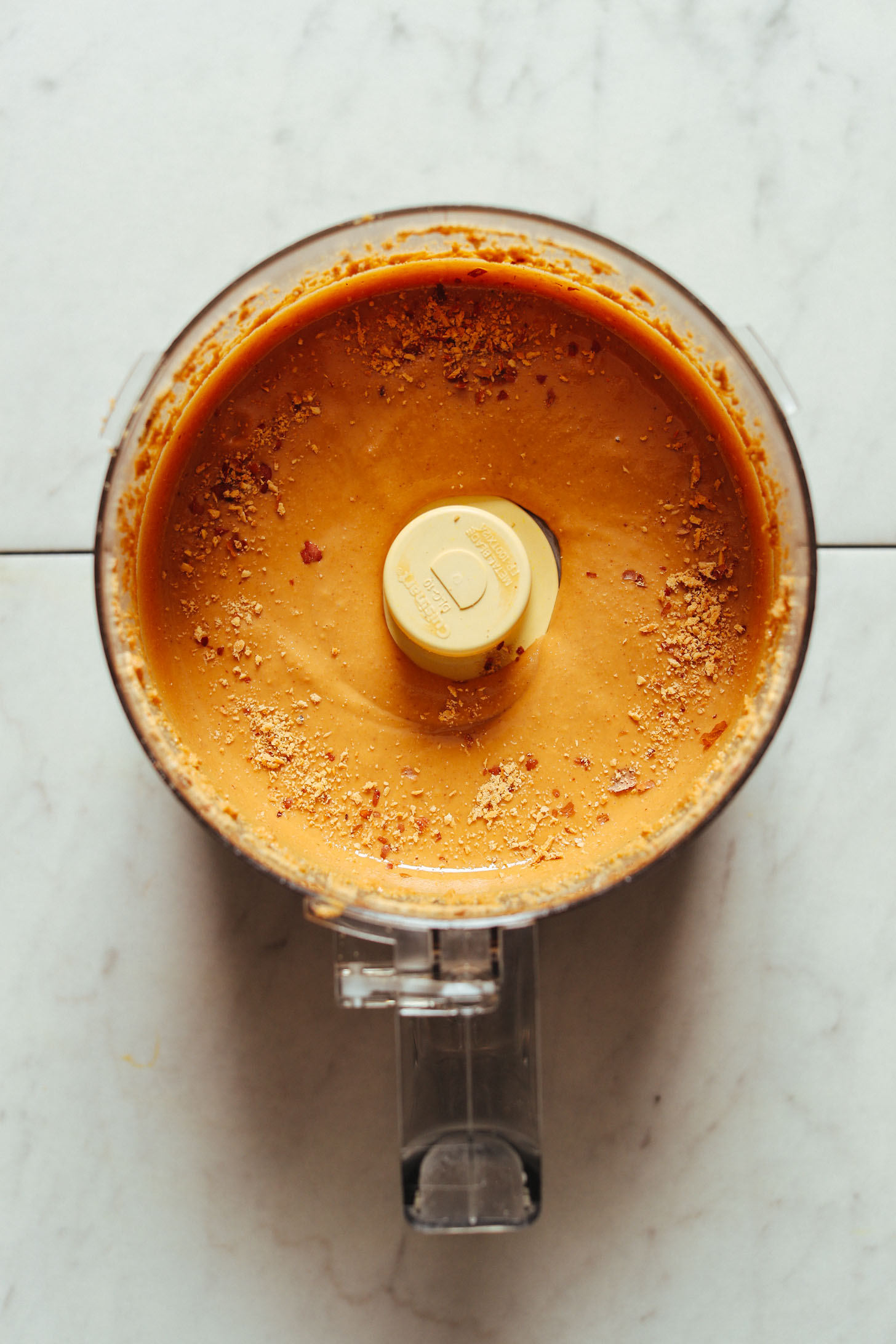 Food processor filled with creamy gluten-free Cinnamon Raisin Peanut Butter