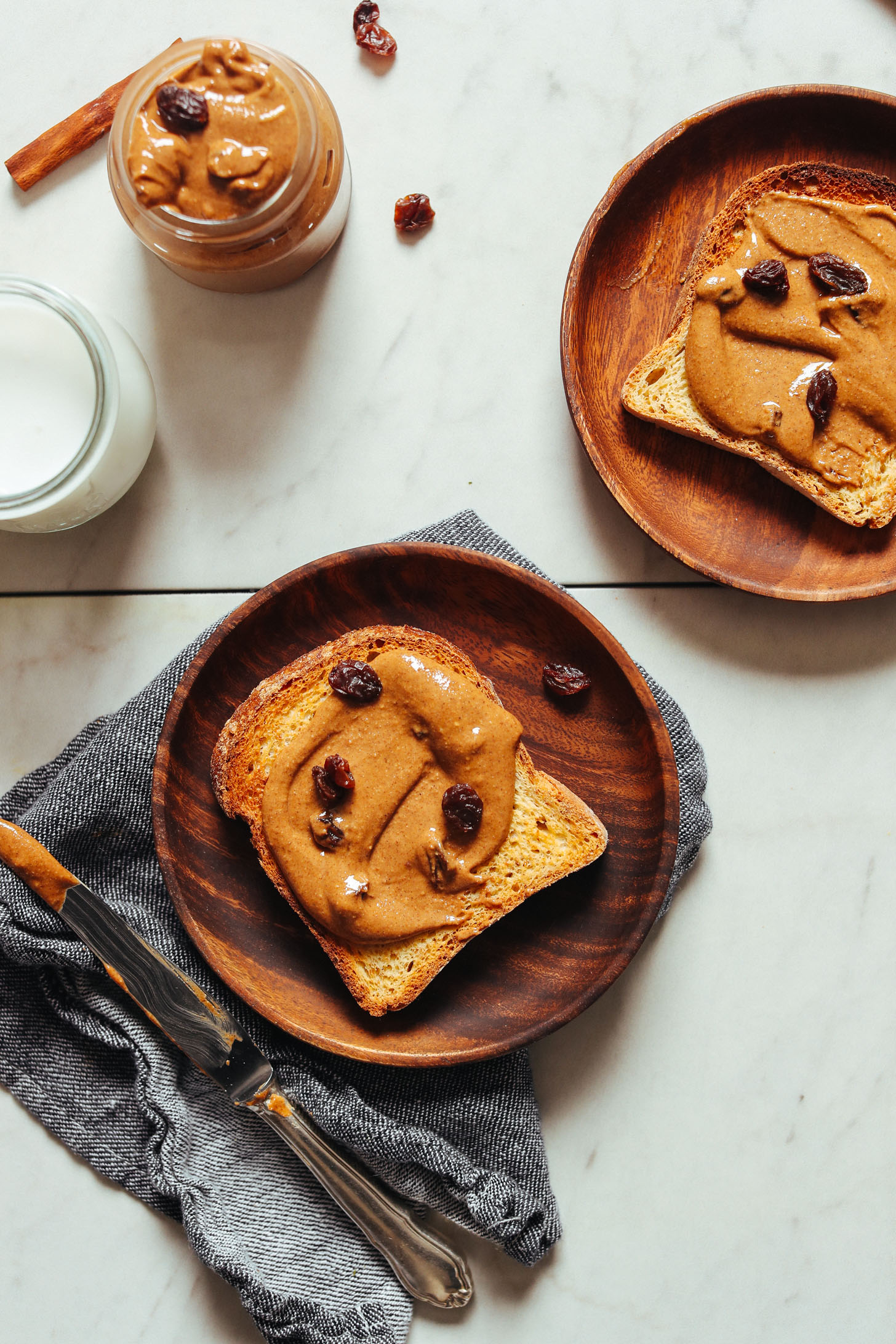 Wood plates featuring slices of gluten-free toast with Cinnamon Raisin Peanut Butter for a delicious plant-based snack