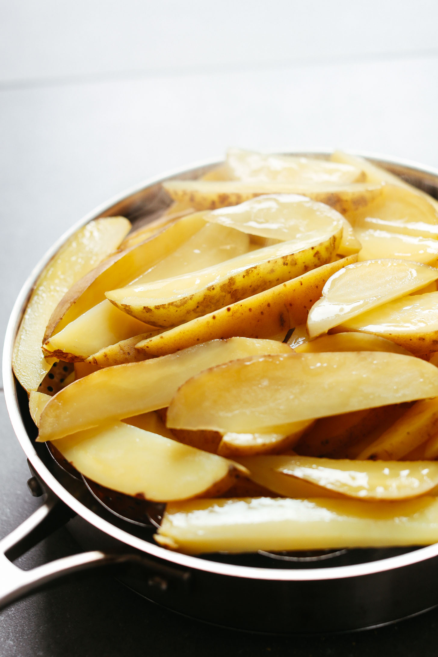 Using a steam basket over a pan to soften potato wedges