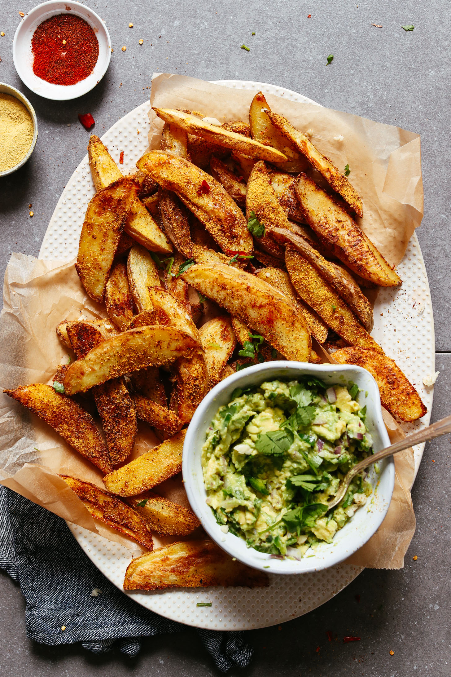 Platter full of Crispy Baked Oil-Free Potato Fries with Cheesy-Chili seasoning and a side of guac