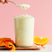 Lifting a spoonful of Mango Coconut Yogurt from a large weck jar