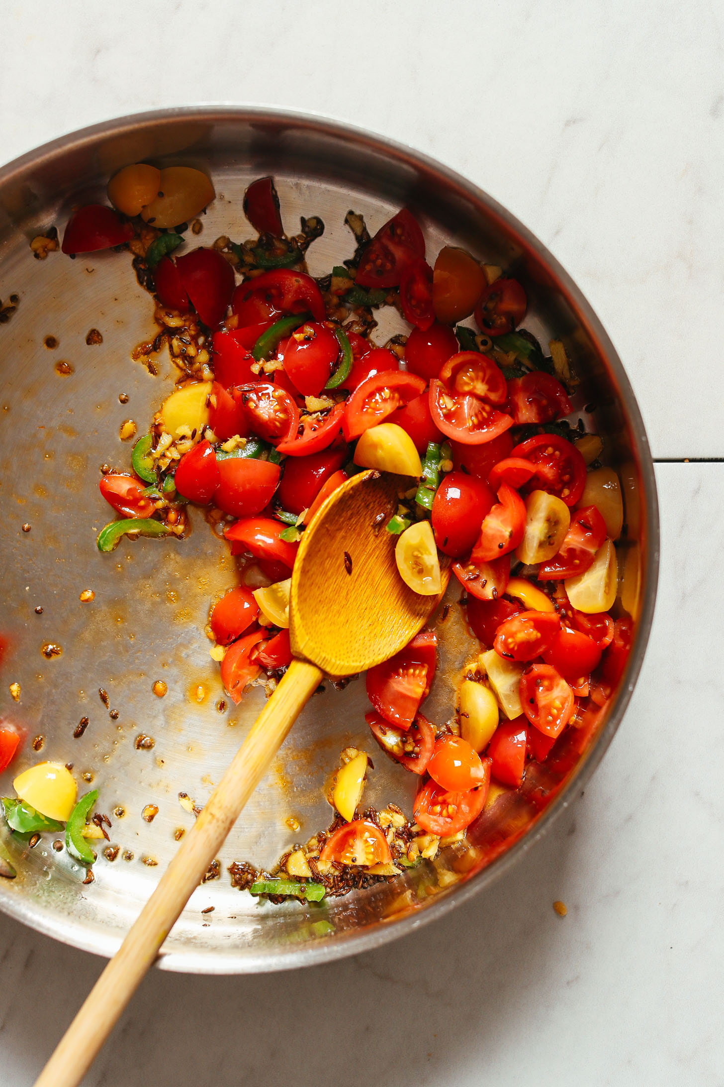 Stirring tomatoes, spices, and serrano for making homemade vegan kitchari