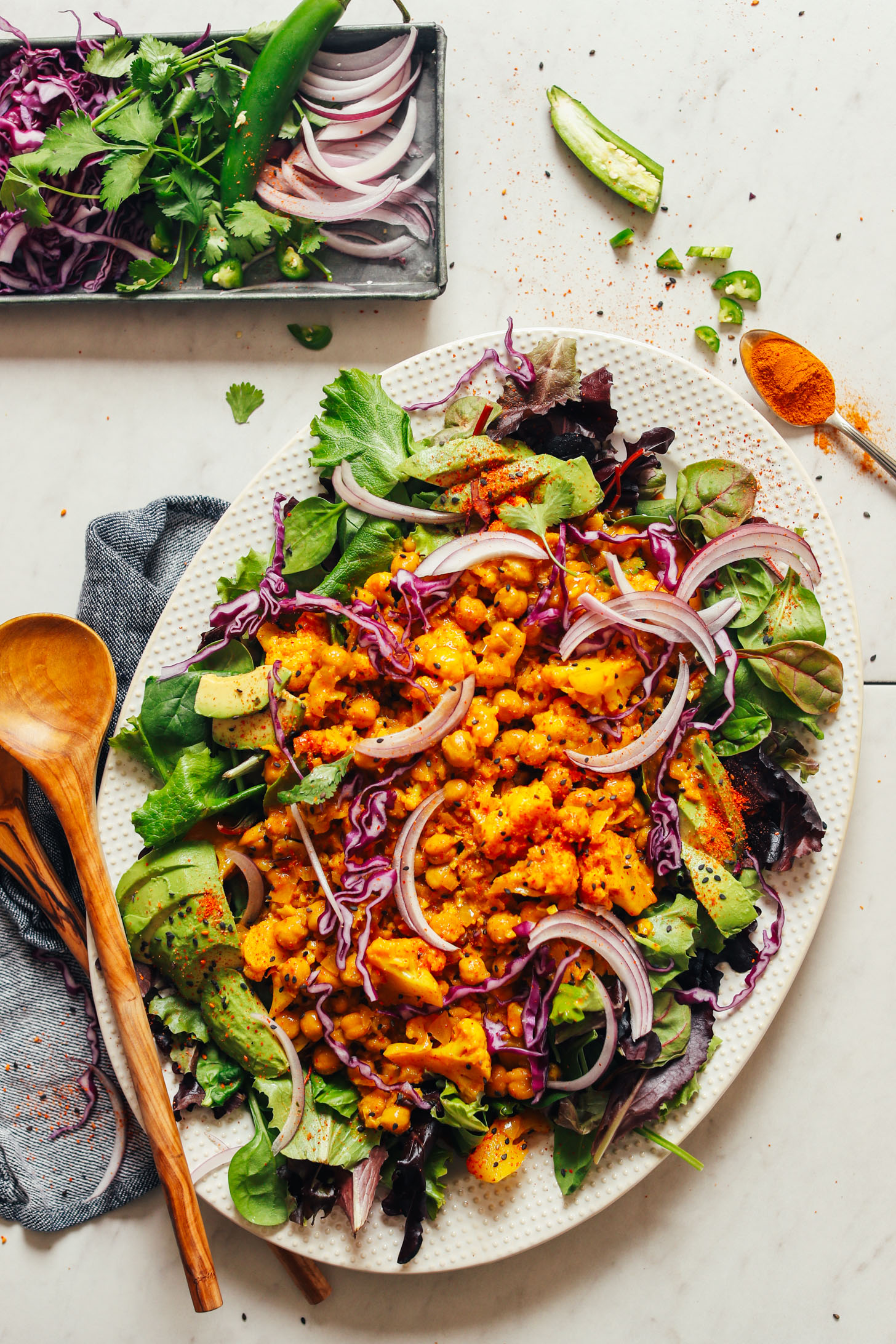 Ceramic platter filled with greens and topped with gluten-free vegan Yellow Chickpea Cauliflower Curry