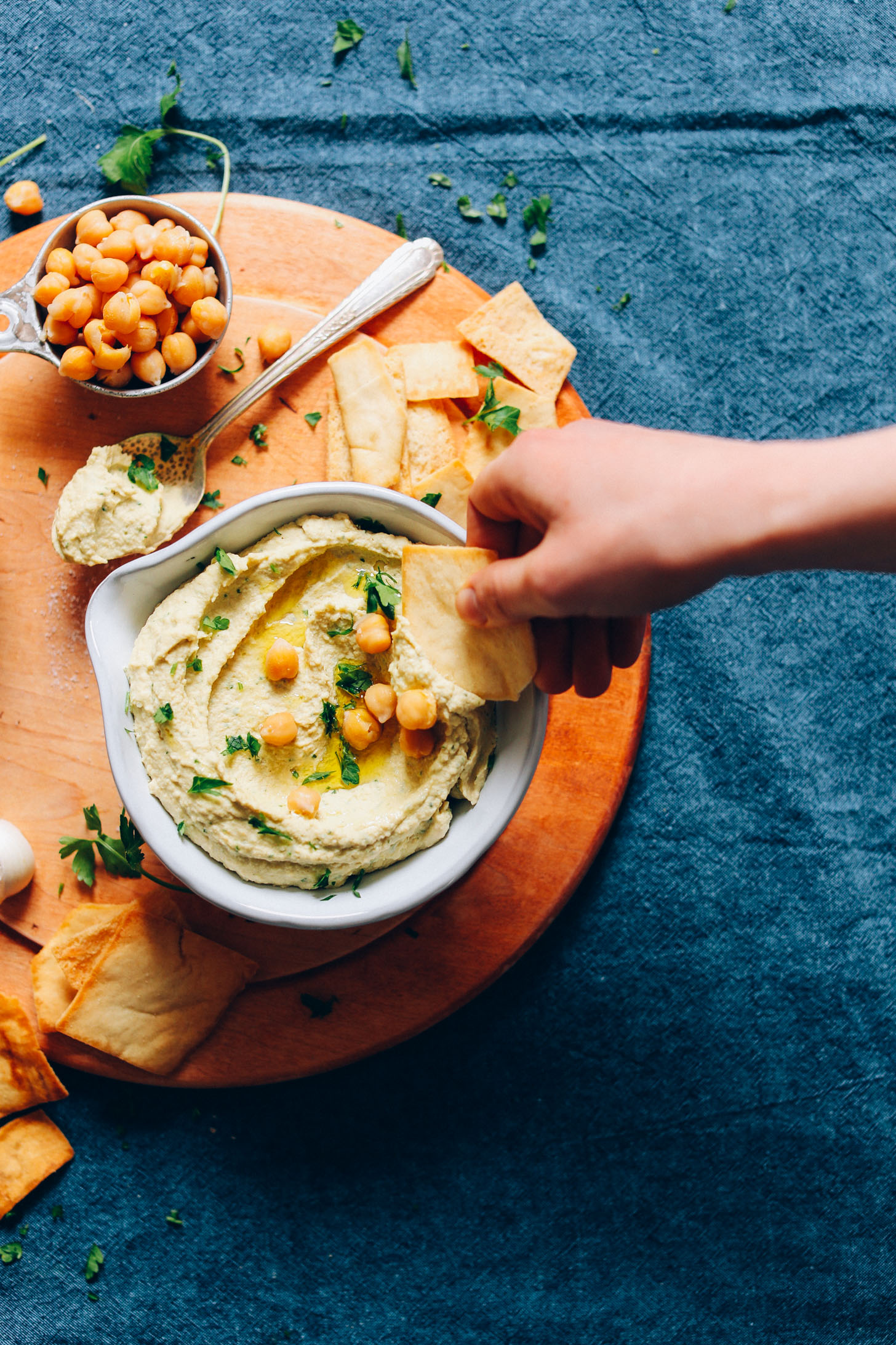 Scooping homemade hummus onto a cracker for a delicious vegan snack