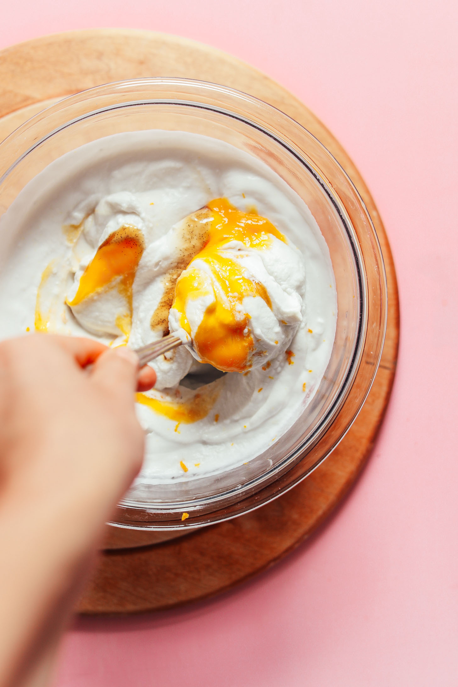 Stirring mango puree into thick and tangy homemade coconut yogurt