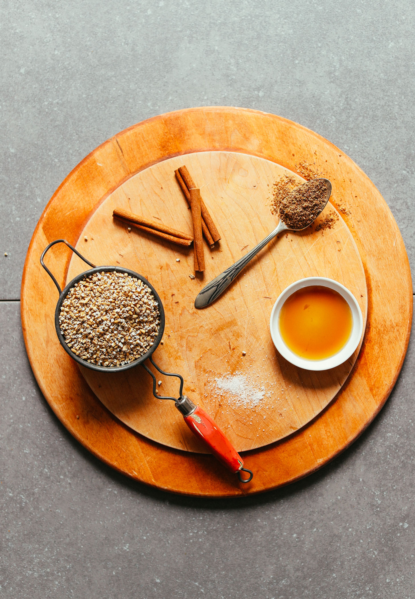 Wood cutting board with steel cut oats, salt, maple syrup, flaxseed meal, and cinnamon for making a delicious gluten-free vegan breakfast