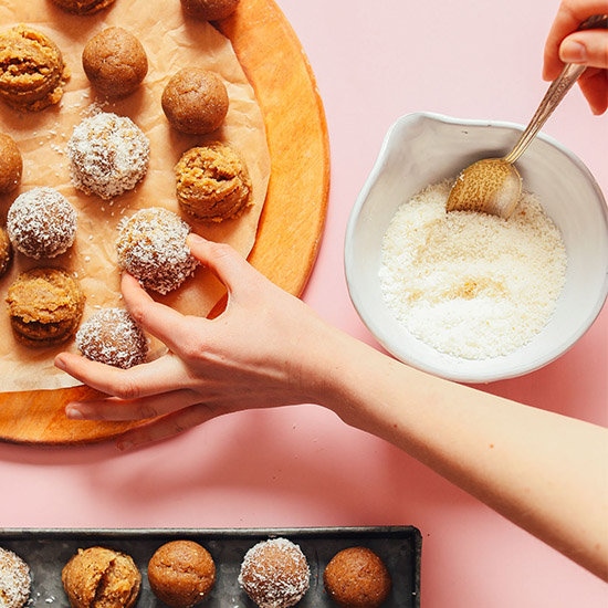 Setting a Vanilla Cake Bite covered in coconut onto a wood cutting board
