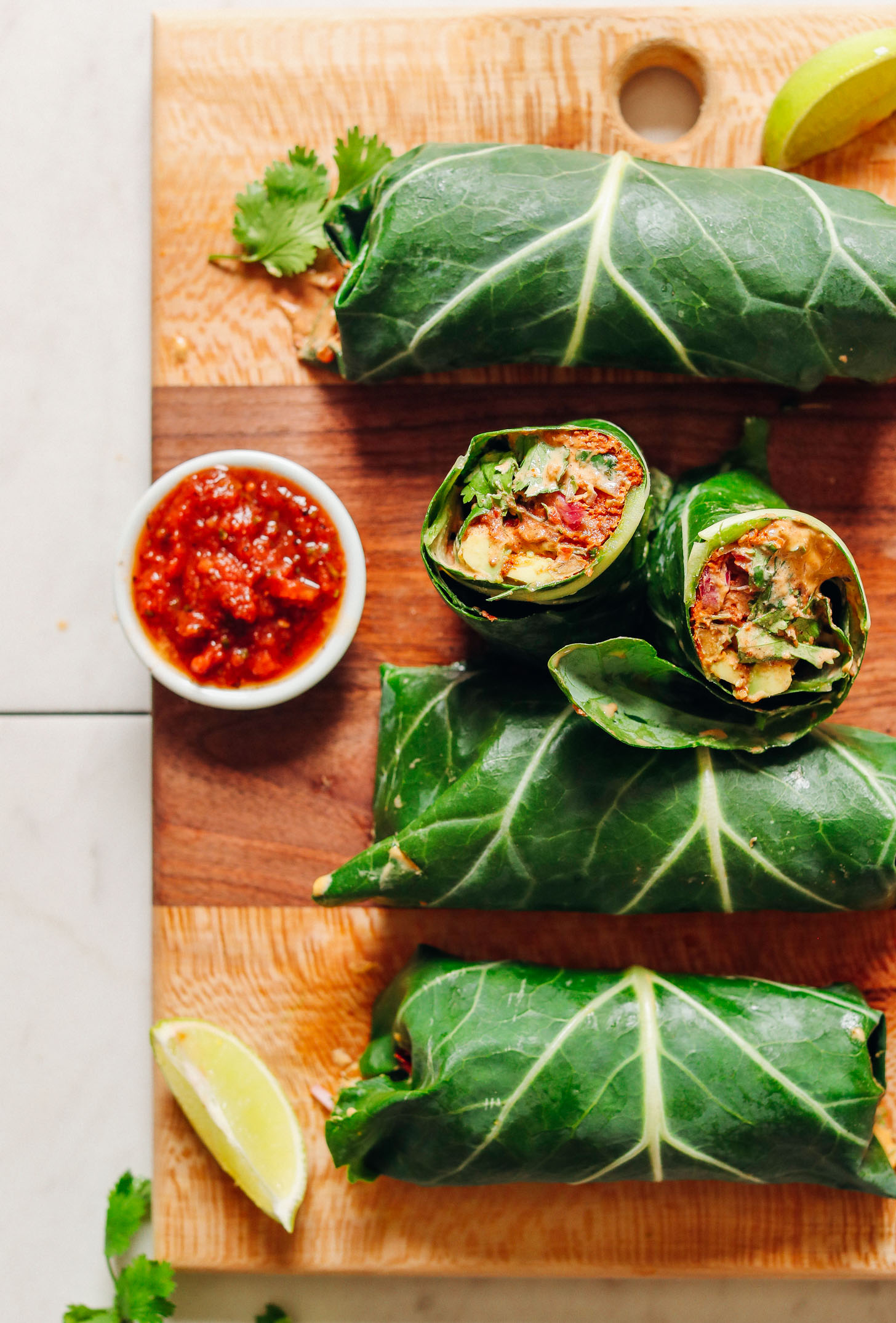 Batch of our Raw Vegan Burritos recipe on a wood cutting board with salsa and lime for serving
