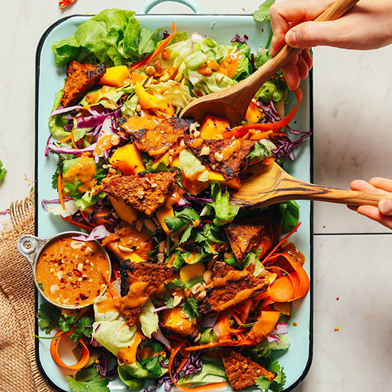 Using wooden salad spoons to grab a serving of our colorful Mango Salad with Peanut Dressing