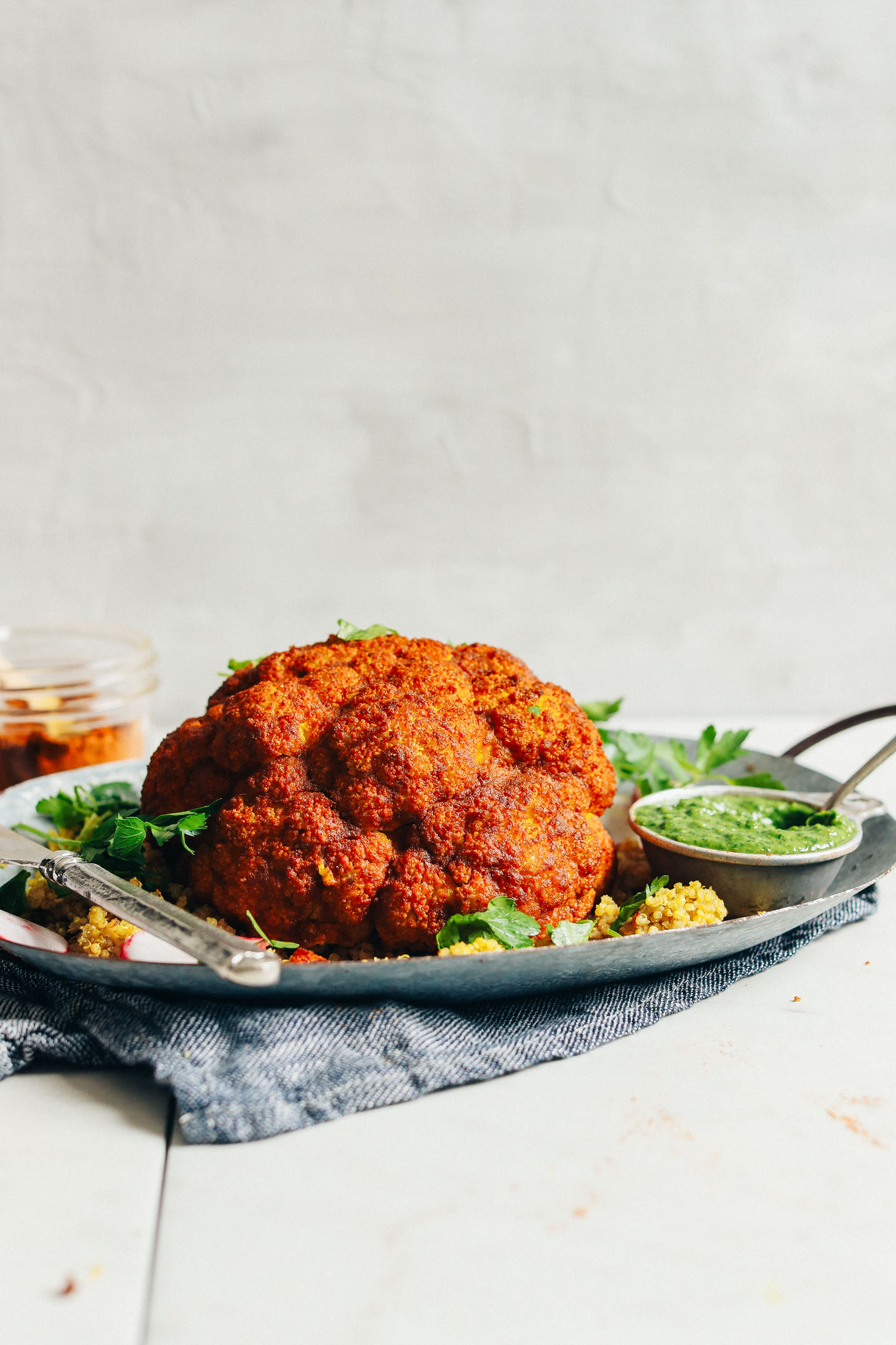 Whole Roasted Cauliflower on a metal platter with a side of chimichurri