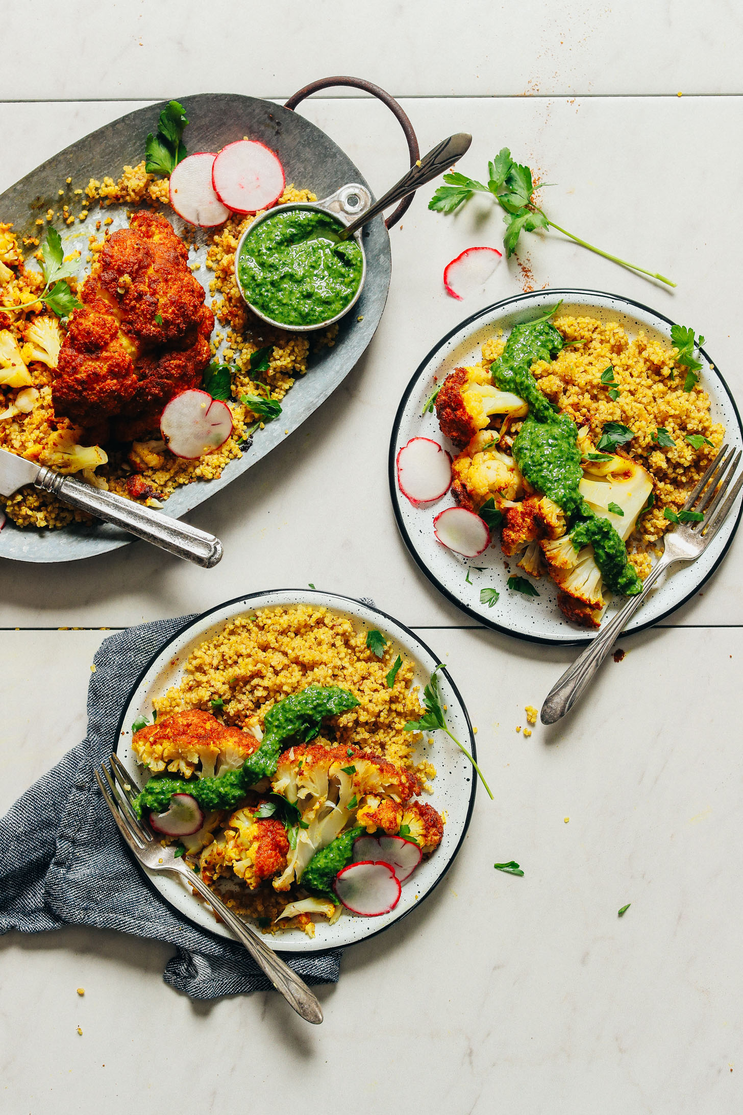 Dinner plates filled with curried quinoa, Shawarma Roasted Cauliflower, and chimichurri