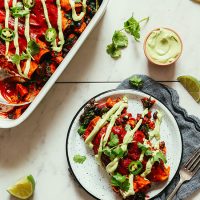 Plate and baking dish filled with our vegan Sweet Potato Black Bean Enchiladas